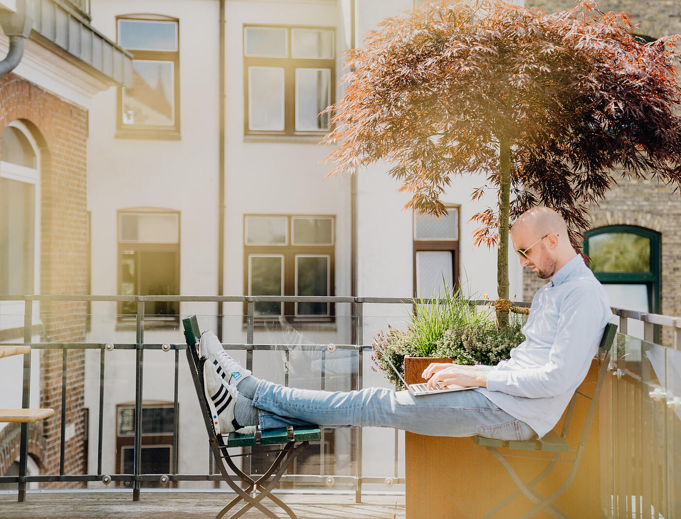 Ein Mitarbeiter von visuellverstehen arbeitet im Sonnenschein auf der Dachterrasse.