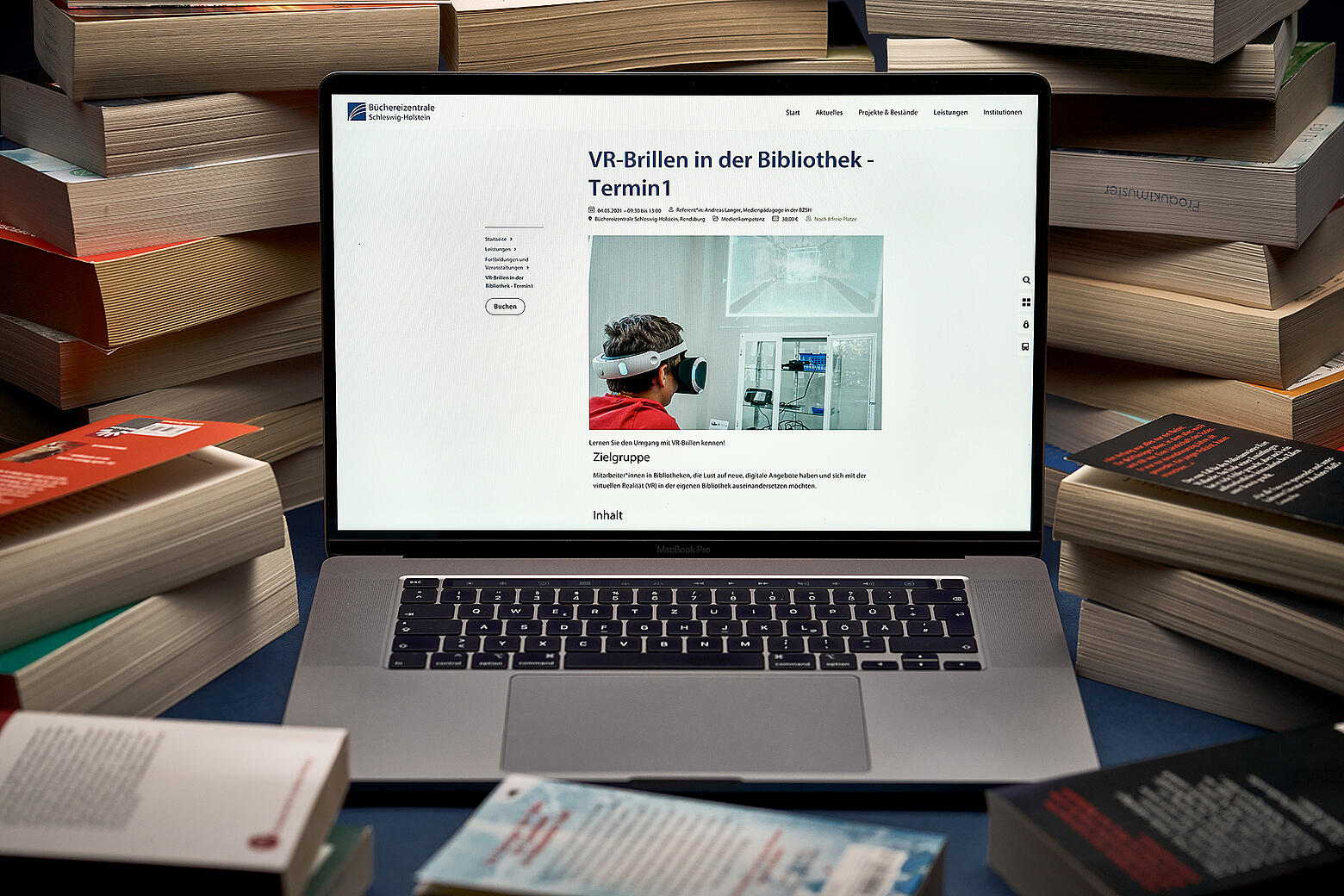 Ein aufgeklapptes Macbook zeigt den neuen Internetauftritt der Büchereizentrale SH inmitten von Bücherstapeln auf einem Tisch.