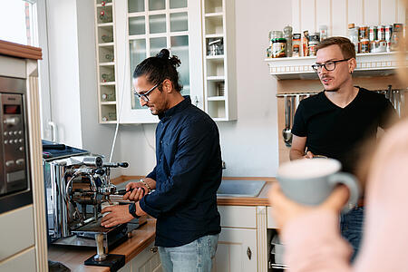 Mehrere Mitarbeitende von visuellverstehen holen sich in der modernen Küche einen Kaffee.