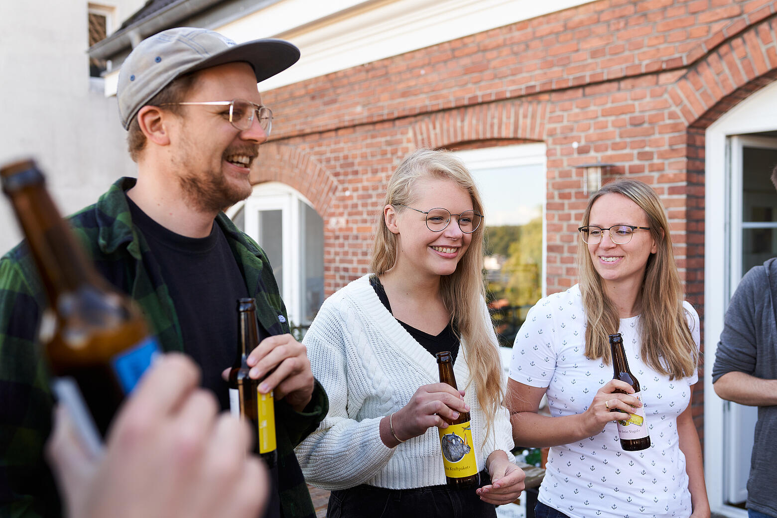 Mehrere Mitarbeitende von visuellverstehen stehen lachend mit Getränken auf dem Balkon.