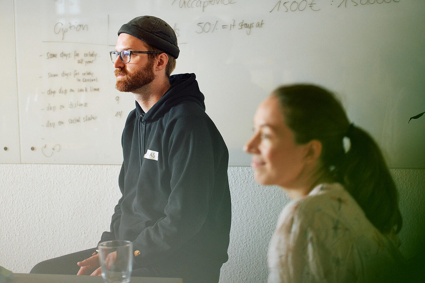 Zwei Mitarbeitende von visuellverstehen sitzen beim Open Friday in einem Kleingruppenmeeting und hören aufmerksam zu.