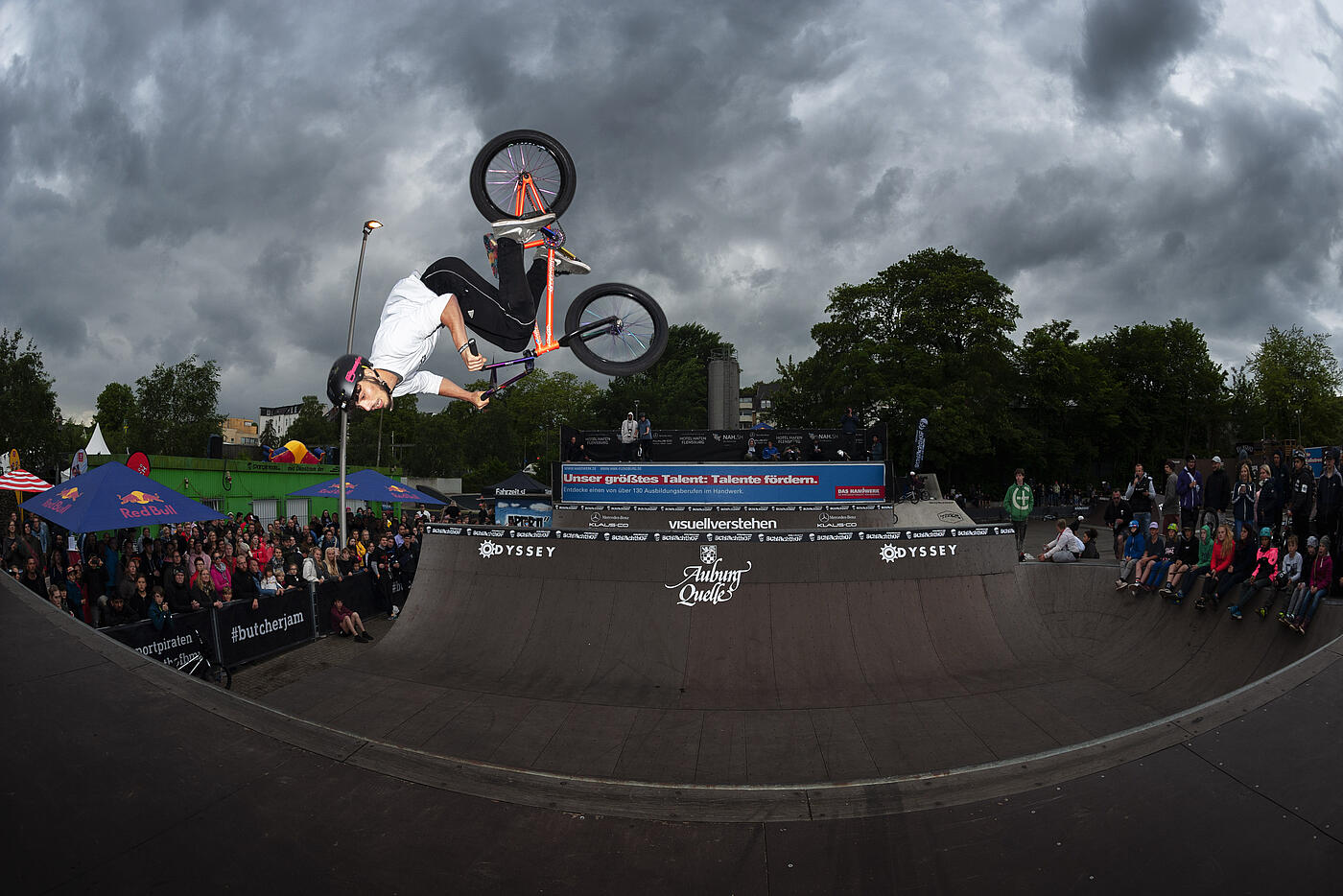 Ein BMX-Fahrer dreht sich am oberen Rand einer Halfpipe in der Luft. Es scheint, als wenn er fällt..