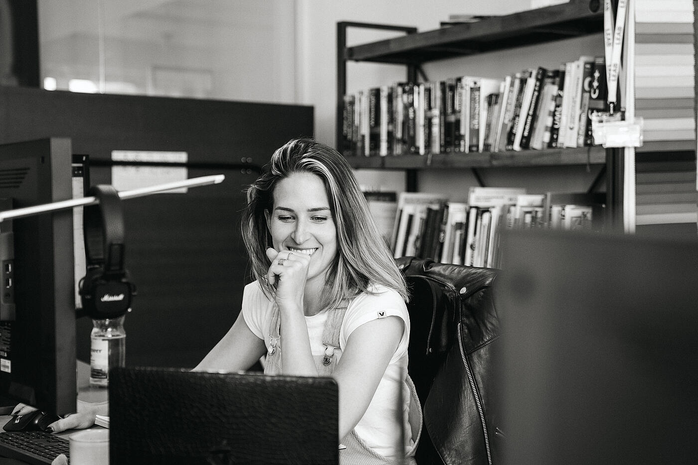 Eine Mitarbeiterin der Agentur visuellverstehen sitzt an ihrem Schreibtisch und schaut auf einen Laptop.