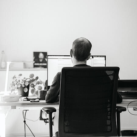 Ein Mitarbeiter an seinem Arbeitsplatz in der Agentur visuellverstehen, von hinten betrachtet.