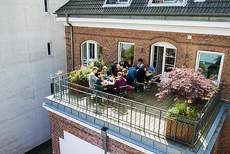 Der einladende Balkon der Werbeagentur visuellverstehen, auf dem Mitarbeitende zu Mittag essen.