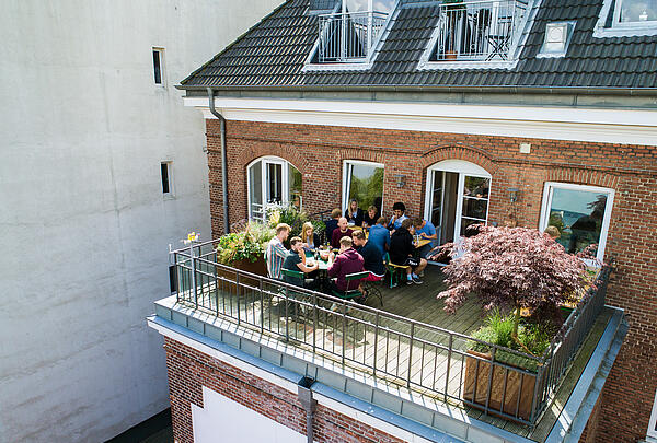 Der einladende Balkon der Werbeagentur visuellverstehen, auf dem Mitarbeitende zu Mittag essen.
