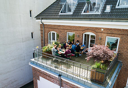 Der einladende Balkon der Werbeagentur visuellverstehen, auf dem Mitarbeitende zu Mittag essen.