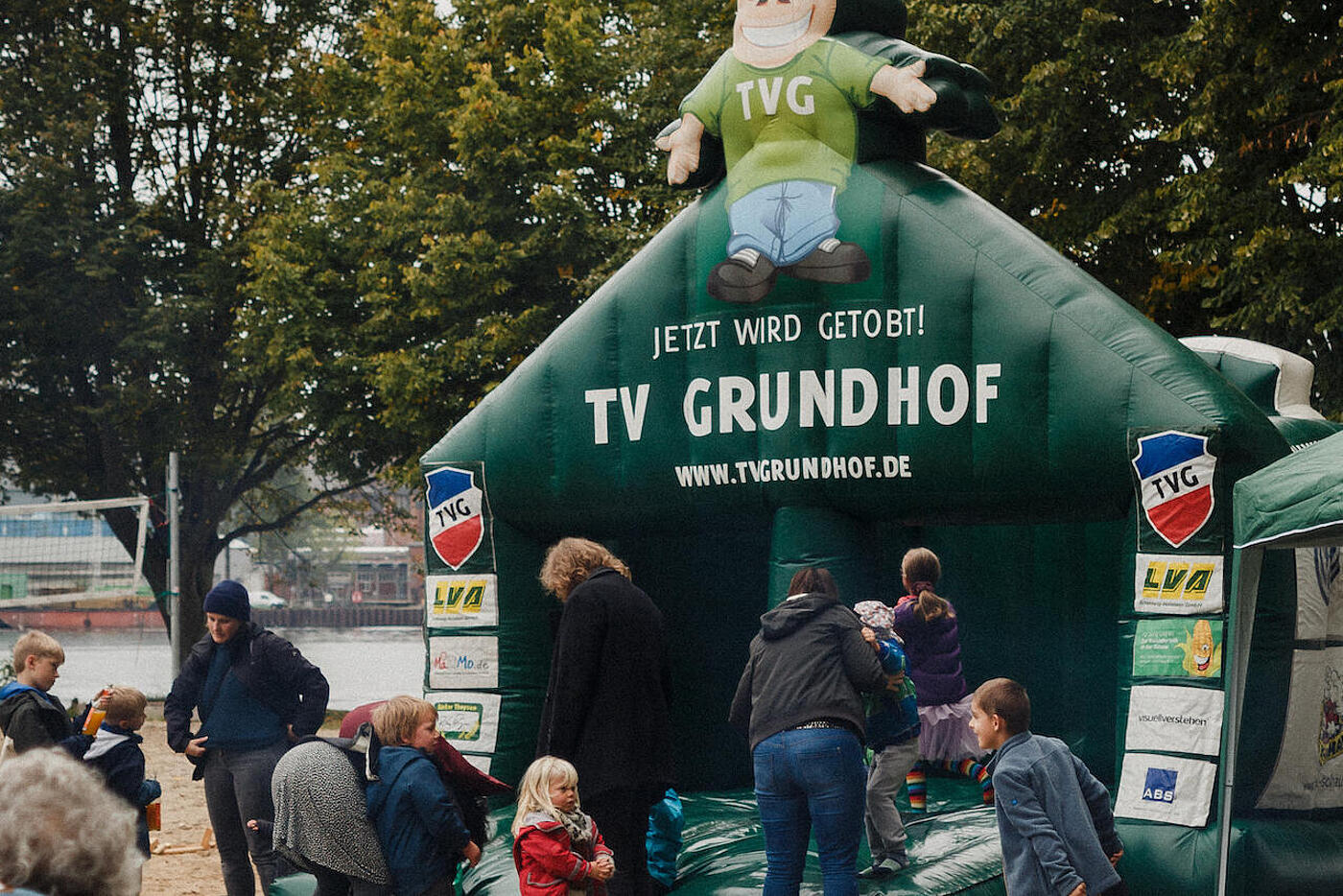 Vor einer dunkelgrünen Hüpfburg drängen sich Eltern und Kinder.