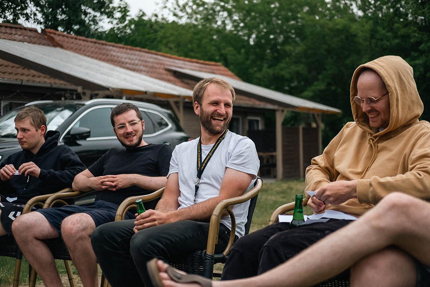 Mitarbeitende von visuellverstehen beim Sommerfest 2022 sitzen in gemütlicher Runde im Freien und lachen.