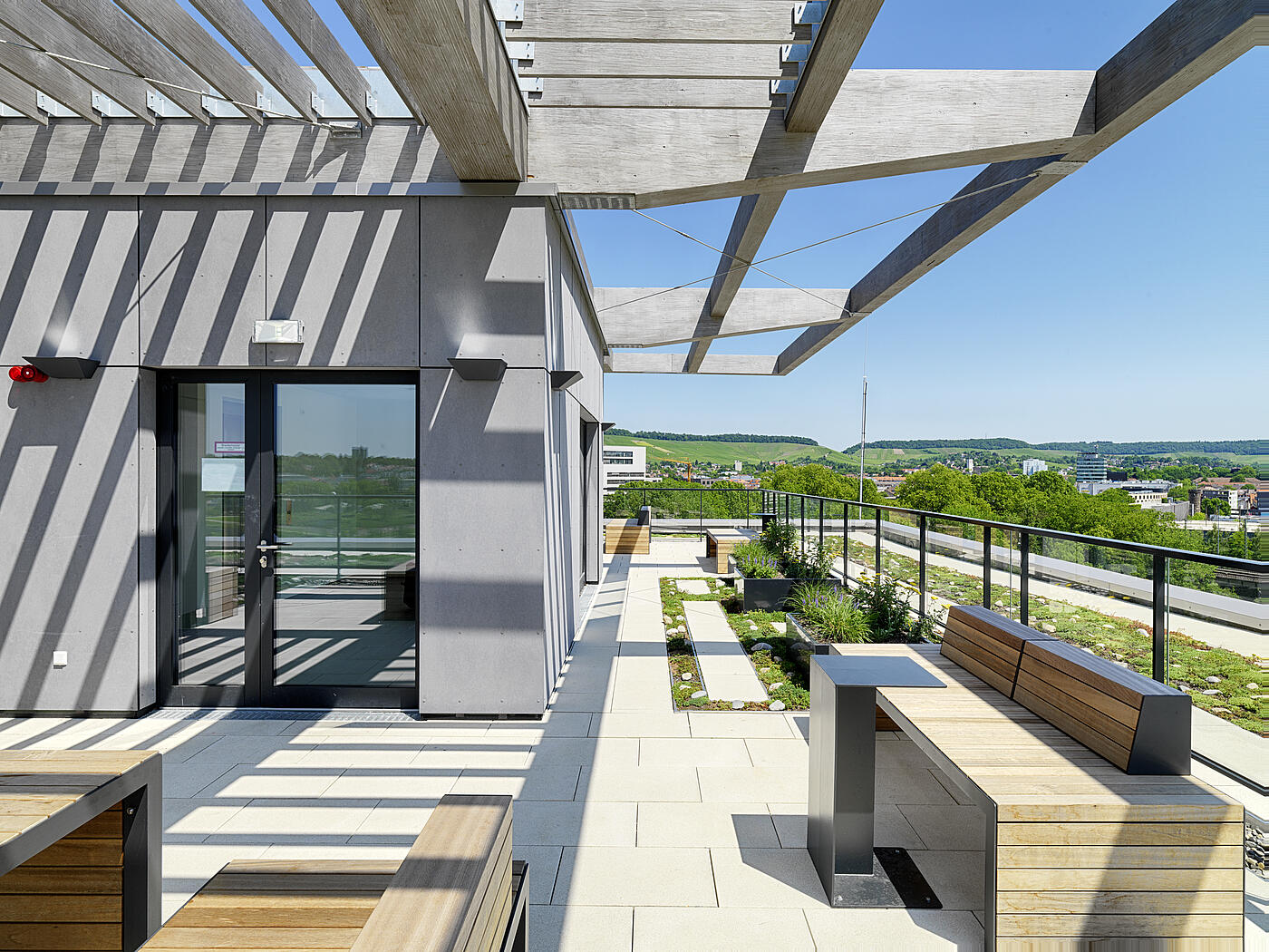 Eine Dachterrasse mit klaren Linien und blauem Himmel im Hintergrund.