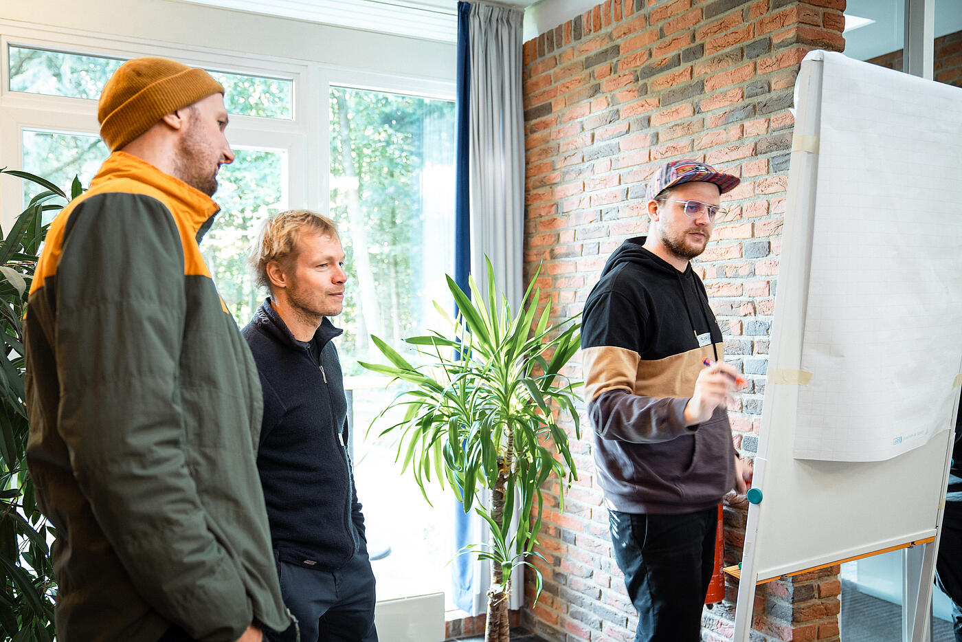 Drei Personen aus dem Team von visuellverstehen bei einer Besprechung an einem FlipChart.