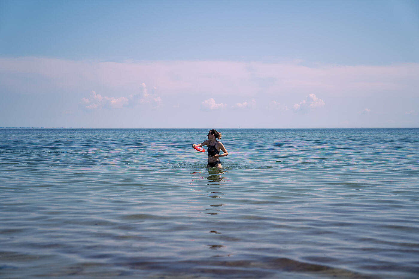 Eine Mitarbeiterin von visuellverstehen spielt im Wasser Frisbee.