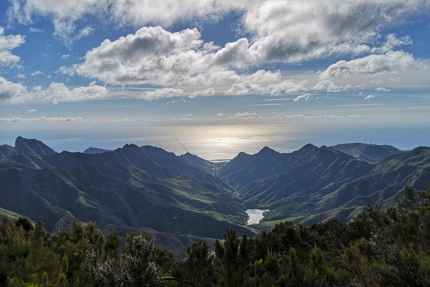 Eine malerische Landschaft mit Bergen und Meer im Hintergrund bei strahlendem Sonnenschein.