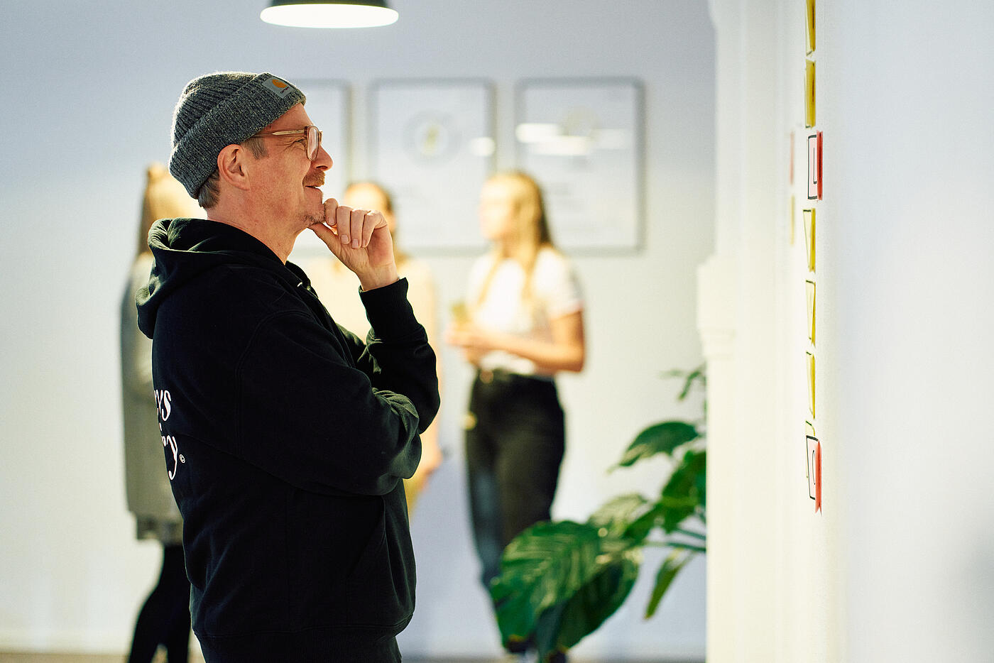 Ein Mitarbeiter von visuellverstehen steht nachdenklich vor einer Wand voller Sticky Notes.