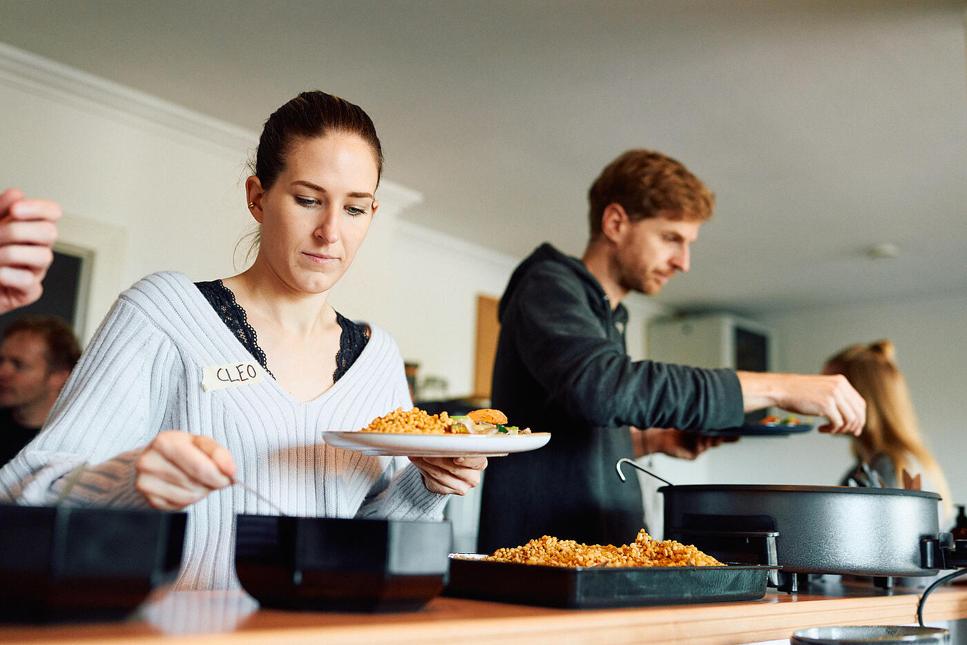 Mitarbeitende von visuellverstehen nehmen sich in der Küche etwas zu essen vom Tresen.