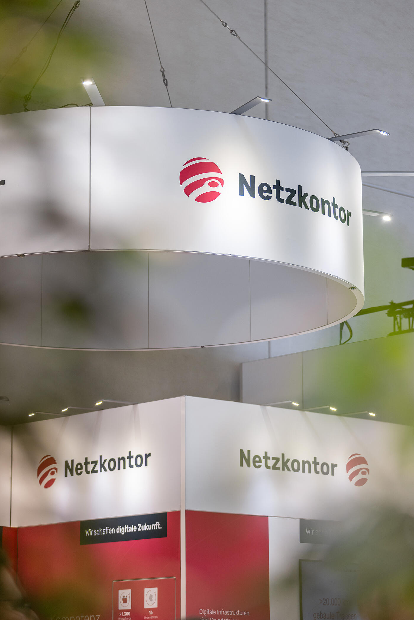 Ein gewölbtes Netzkontor-Banner, das auf einer Messe über dem Netzkontormessestand von der Decke hängt.