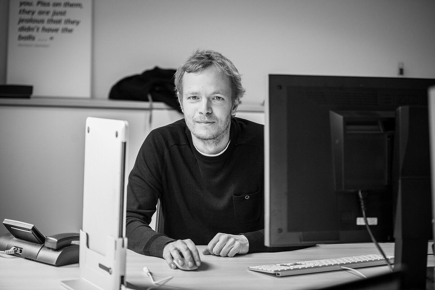 Schwarz-weiß-Bild von Timon an einem Schreibtisch.