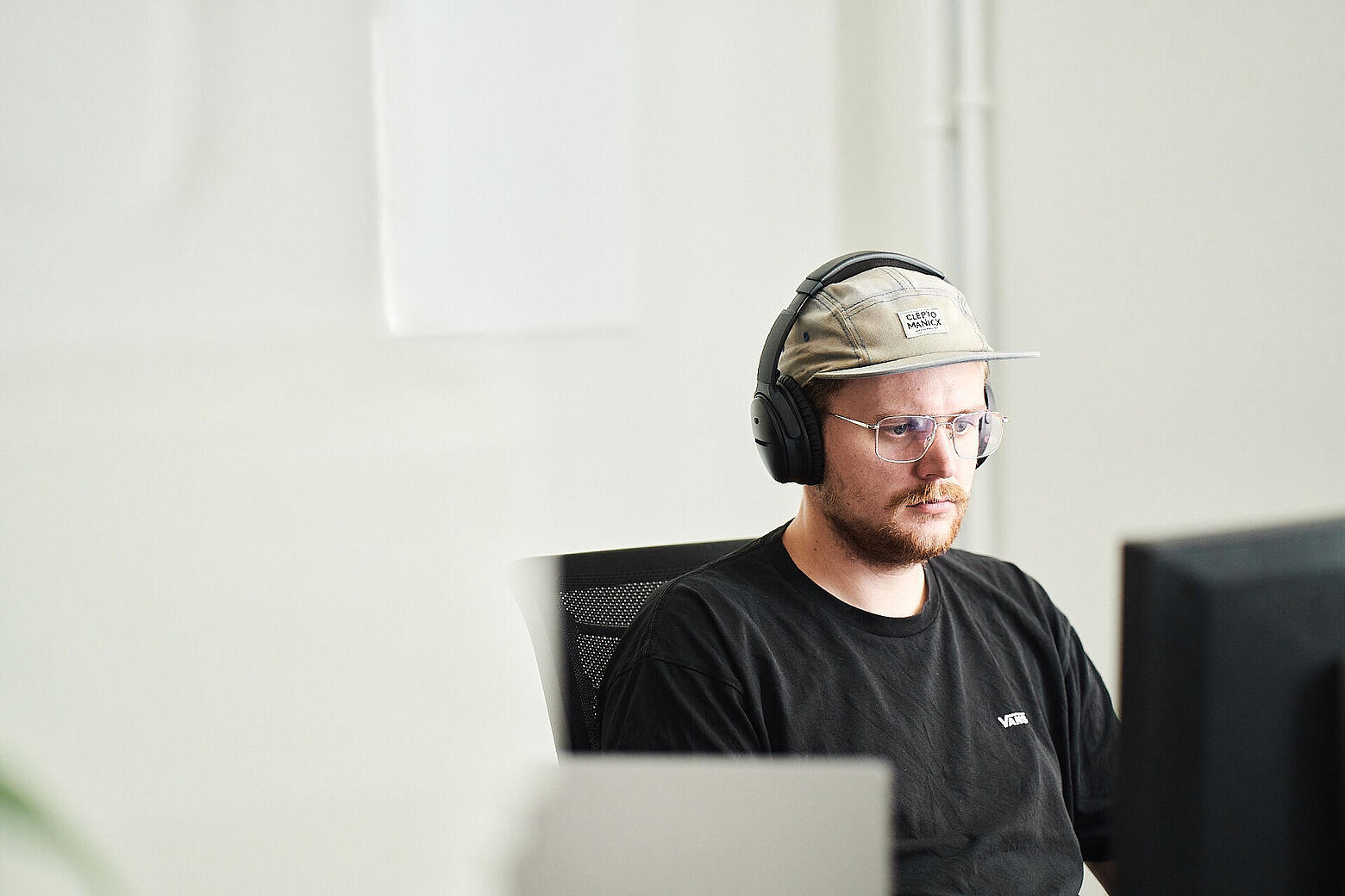 Ein Mitarbeiter von visuellverstehen sitzt mit Kopfhörern am Computer.