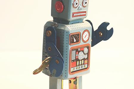 Ein grauer Roboter mit roten Füßen und einem Schraubenschlüssel als Hand.