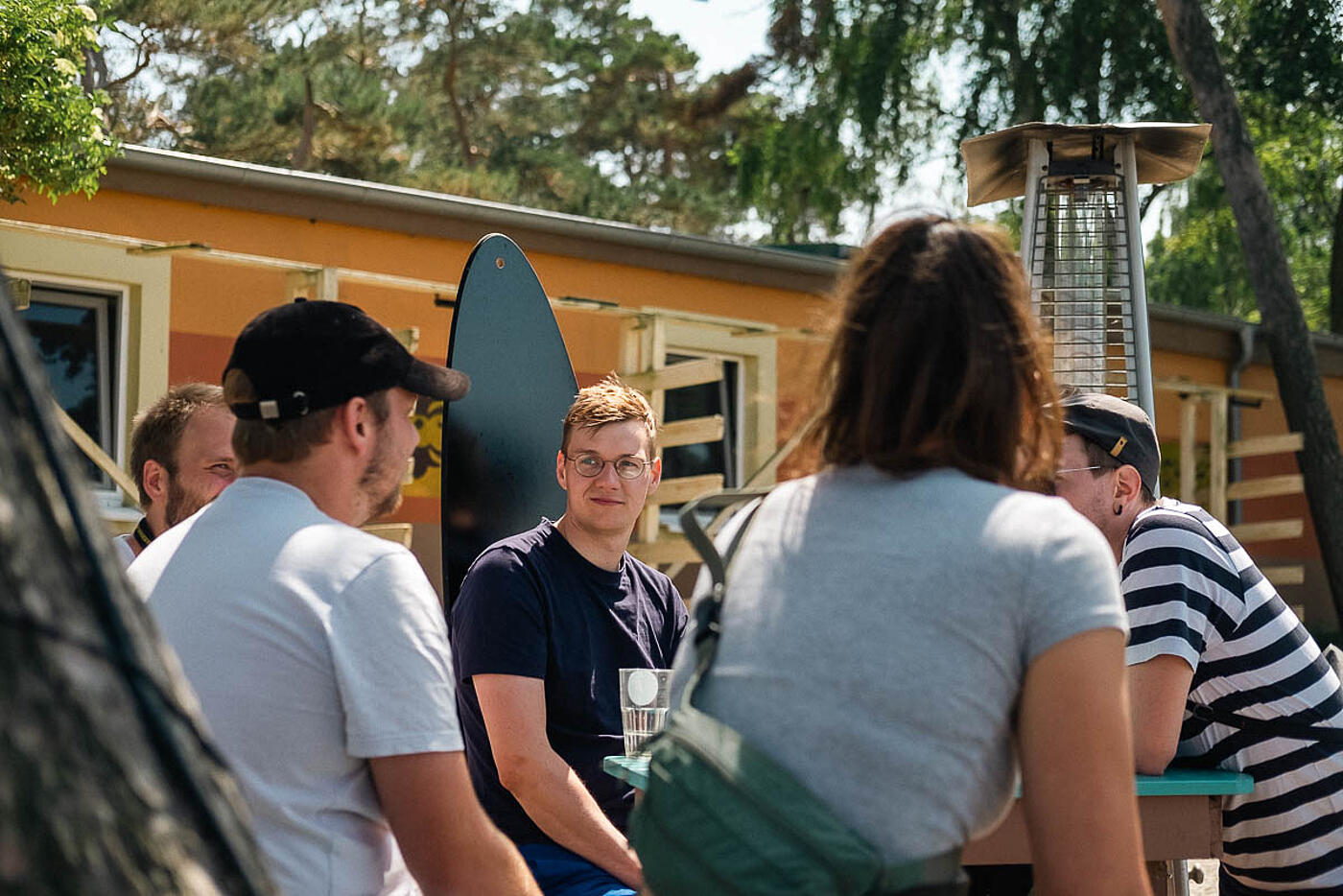 Mitarbeitende von visuellverstehen beim Sommerfest 2022 sitzen in gemütlicher Runde im Freien und unterhalten sich.