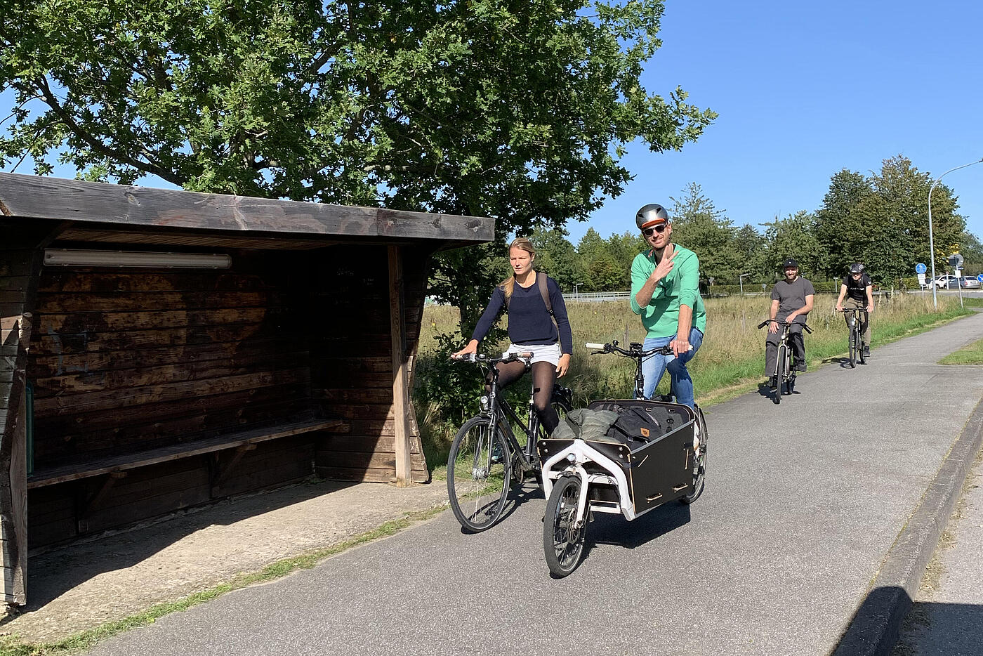 Zwei Mitarbeitende von visuellverstehen fahren Fahrrad, im Hintergrund Wiesen und blauer Himmel. 