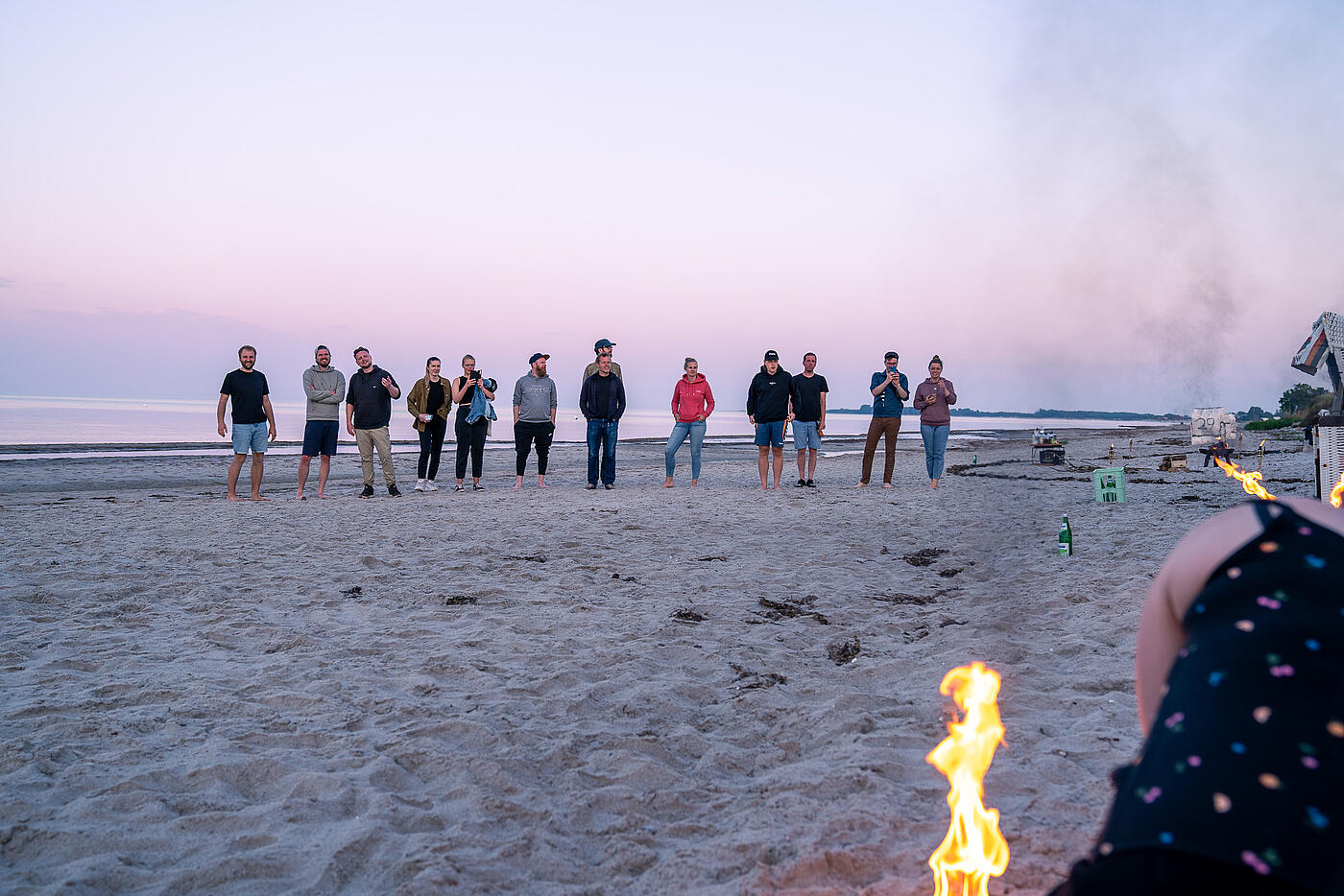 Mitarbeitende von visuellverstehen bestaunen abends am Strand eine Feuershow.