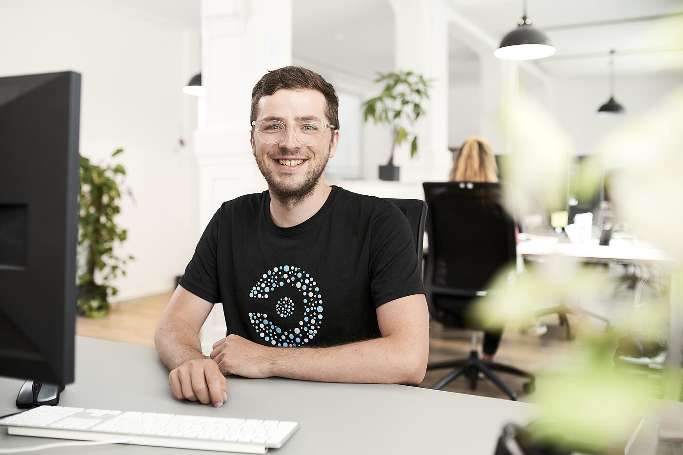 Porträt eines Mitarbeiters von visuellverstehen an seinem Arbeitsplatz in den modernen Büroräumen der Agentur.
