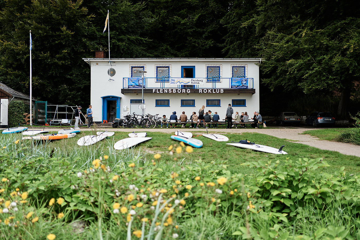 Das Team von visuellverstehen sitzt vor dem Flensburger Ruderklub an einer langen Tafel und isst.