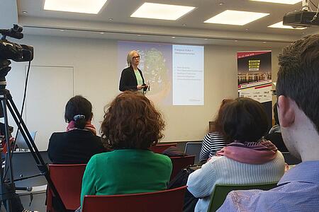 Viele Personen verfolgen bei der Social-Media-Week in Hamburg den Vortrag einer Dozentin in einem hellen Raum.