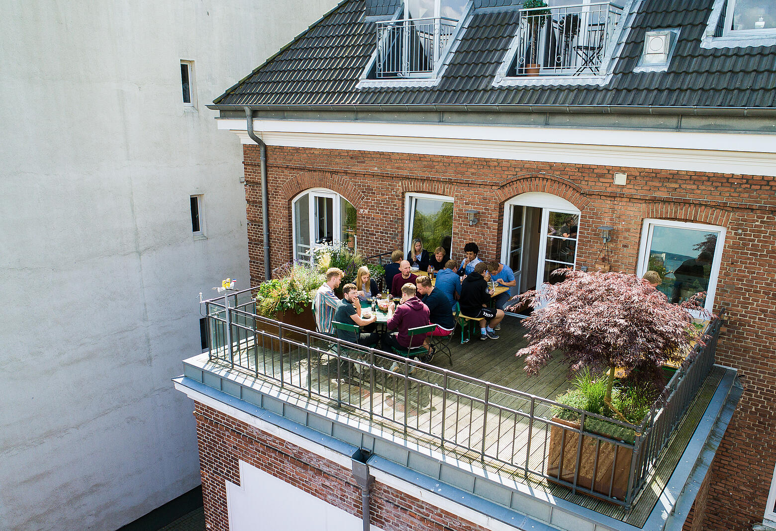 Mehrere Mitarbeiter von visuellverstehen essen zusammen auf dem Balkon.