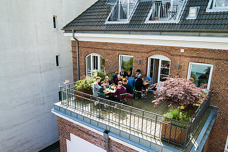 Mehrere Mitarbeiter von visuellverstehen essen zusammen auf dem Balkon.