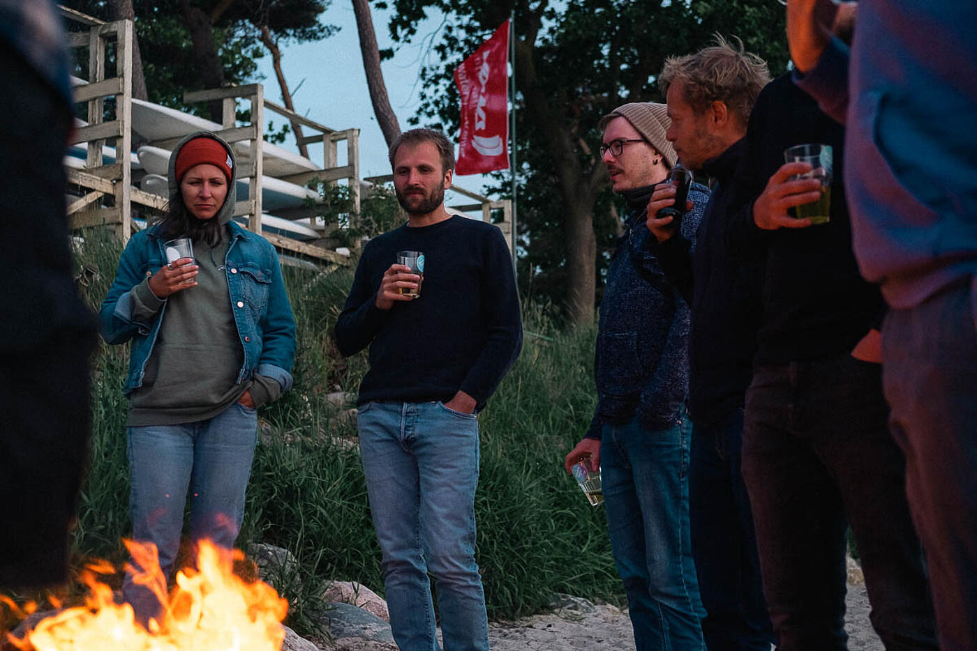 Mehrere Mitarbeitende von visuellverstehen stehen abends am Lagerfeuer.