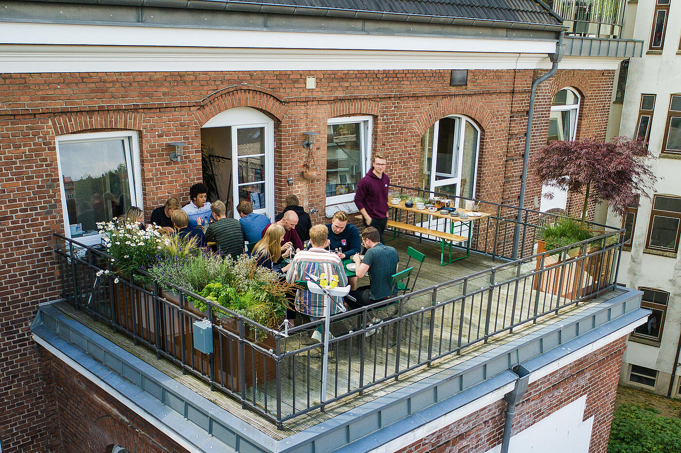 Mehrere Mitarbeiter von visuellverstehen essen zusammen auf dem Balkon.