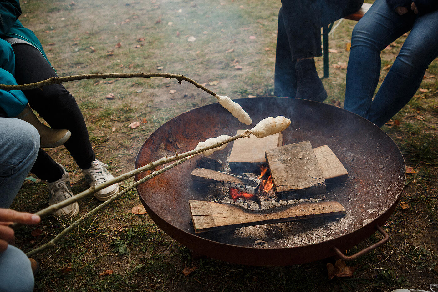 Stockbrot wird über ein Feuerbecken gehalten.