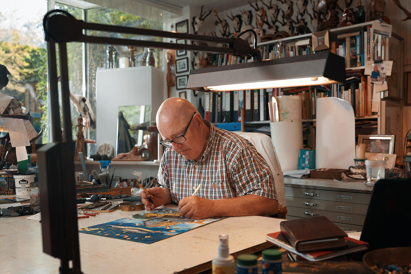 Der Künstler Hans Ruprecht Leiß arbeitet in seinem Atelier konzentriert an einer Zeichnung.
