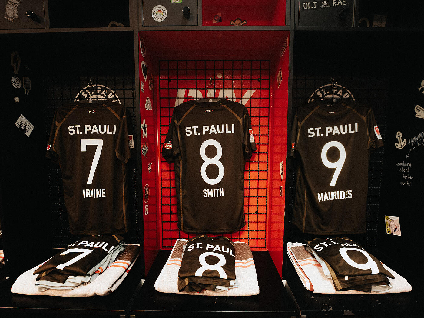 Mehrere FC St. Pauli-Trikots hängen und liegen in der Umkleide aus.