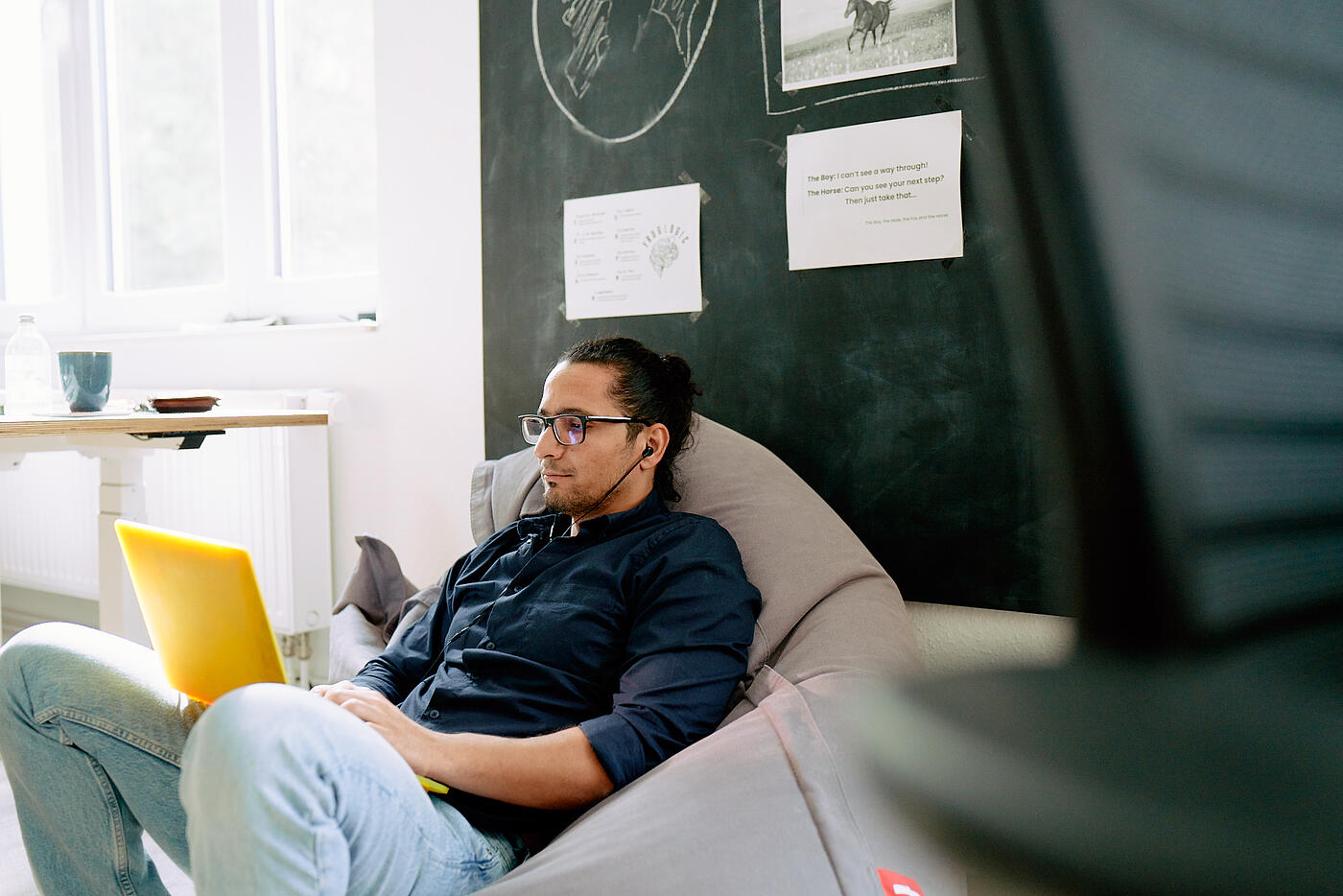 Ein Mitarbeiter aus dem visuellverstehen-Team sitzt entspannt in einem Sitzsack, während er arbeitet.