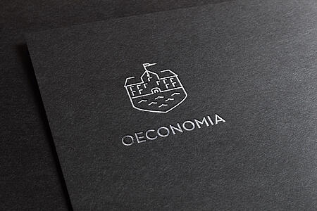 Das Logo der Oeconomia, silbern eingeprägt in einen schwarzen Buchdeckel.