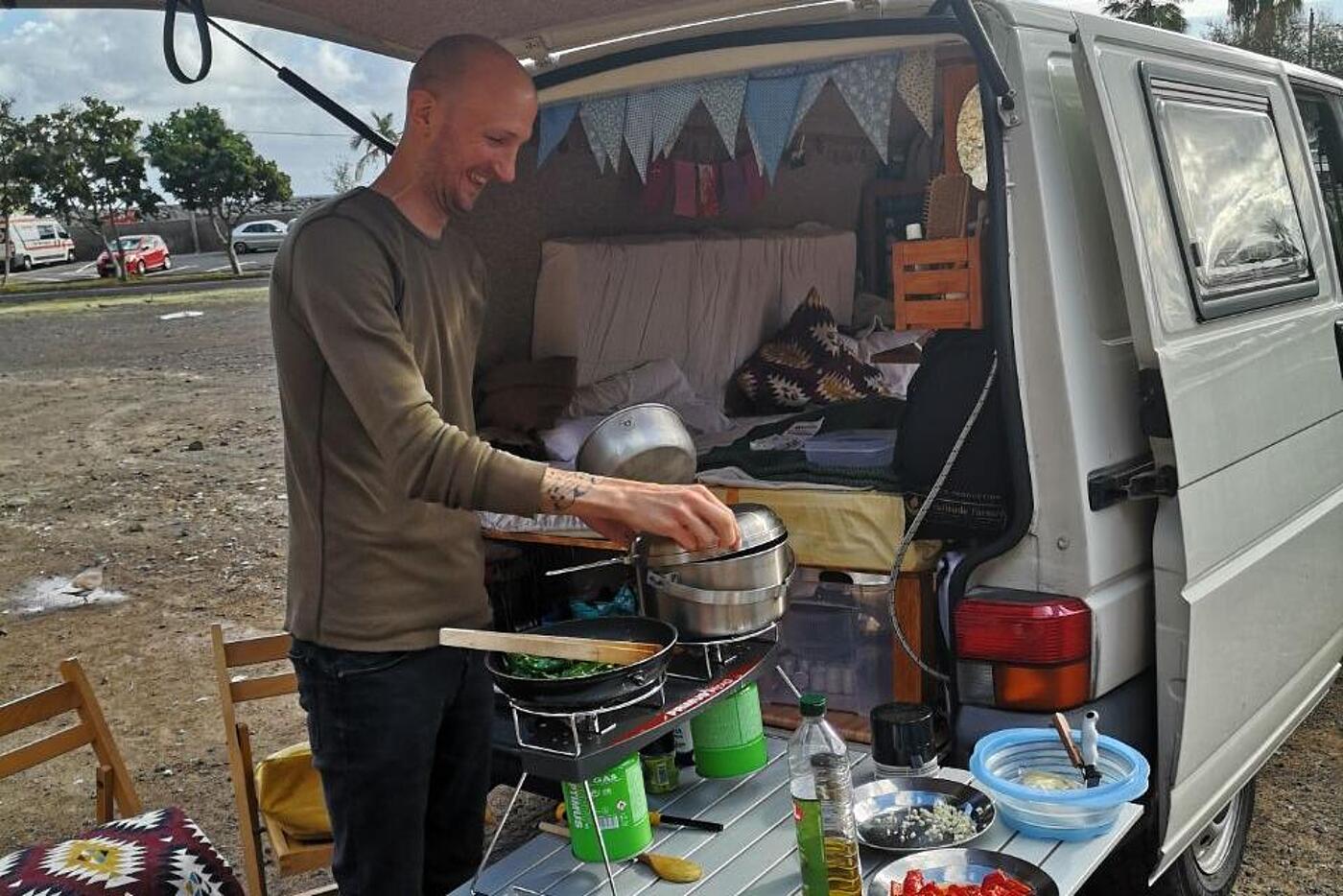 visuellverstehen-Mitarbeiter Flo während seines Kurzsabbaticals: Er kocht vorm VW-Bus. 