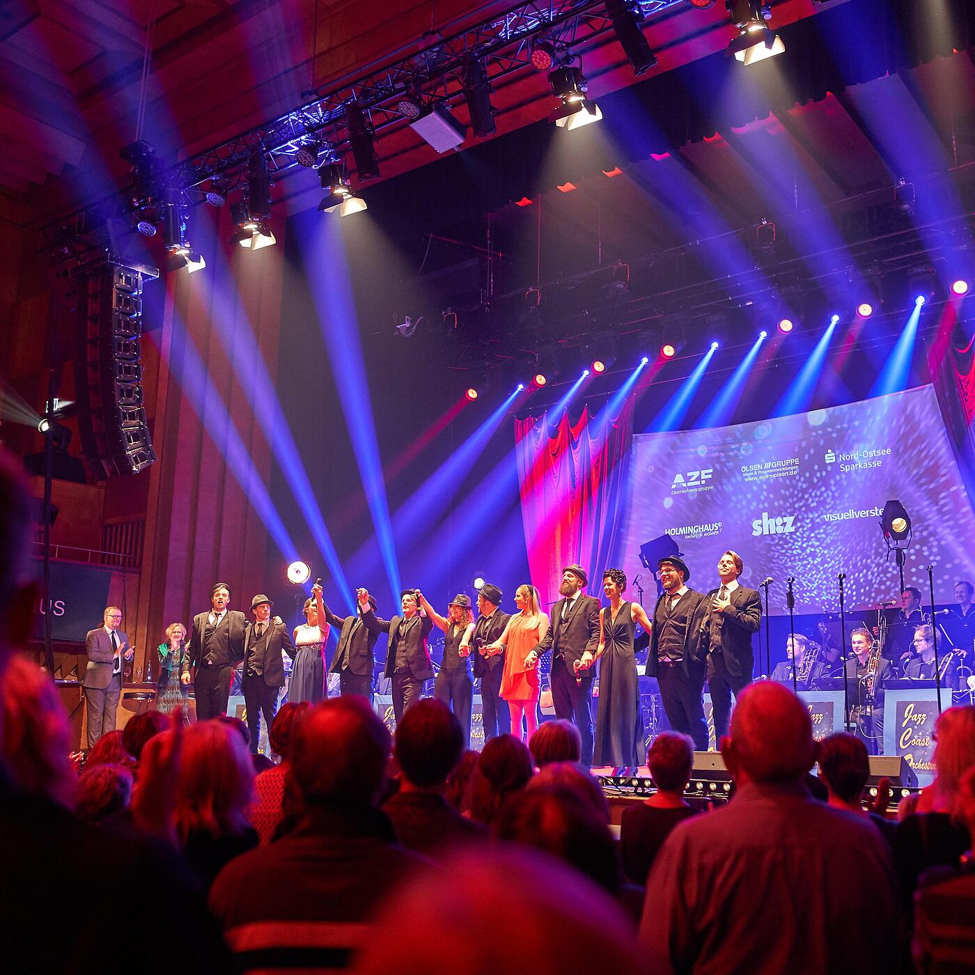 Personen nehmen auf der Flensburg-singt-Sinatra-Veranstaltung Applaus entgegen.