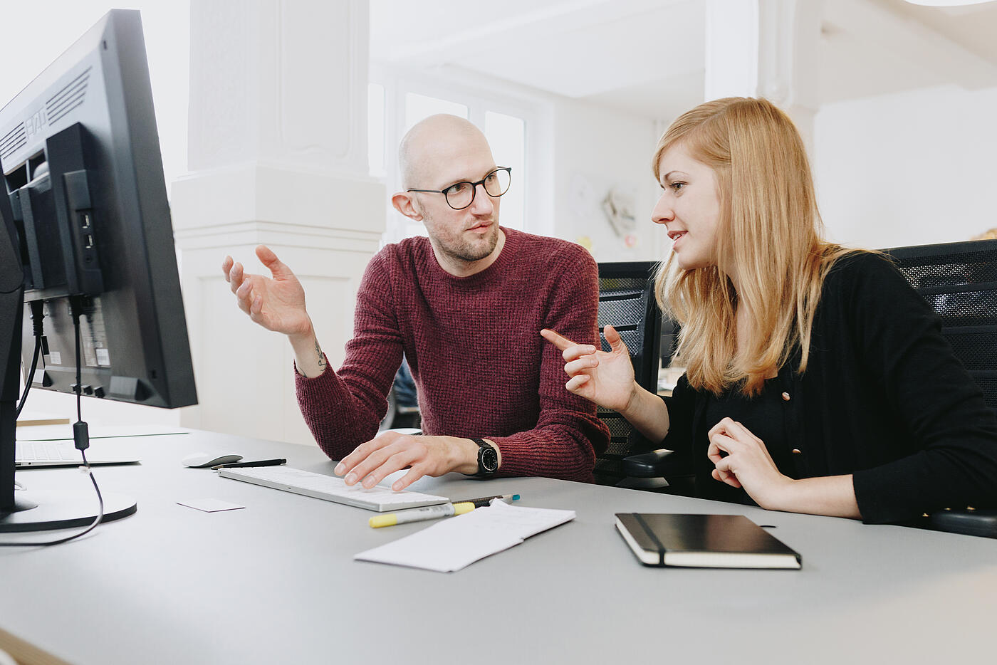 Zwei Mitarbeitende von visuellverstehen diskutieren am Arbeitsplatz.