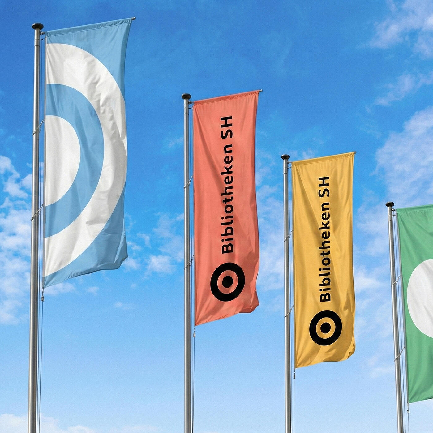 Vier verschiedenfarbige Flaggen mit dem Branding von Bibliotheken SH vor blauem Himmel.