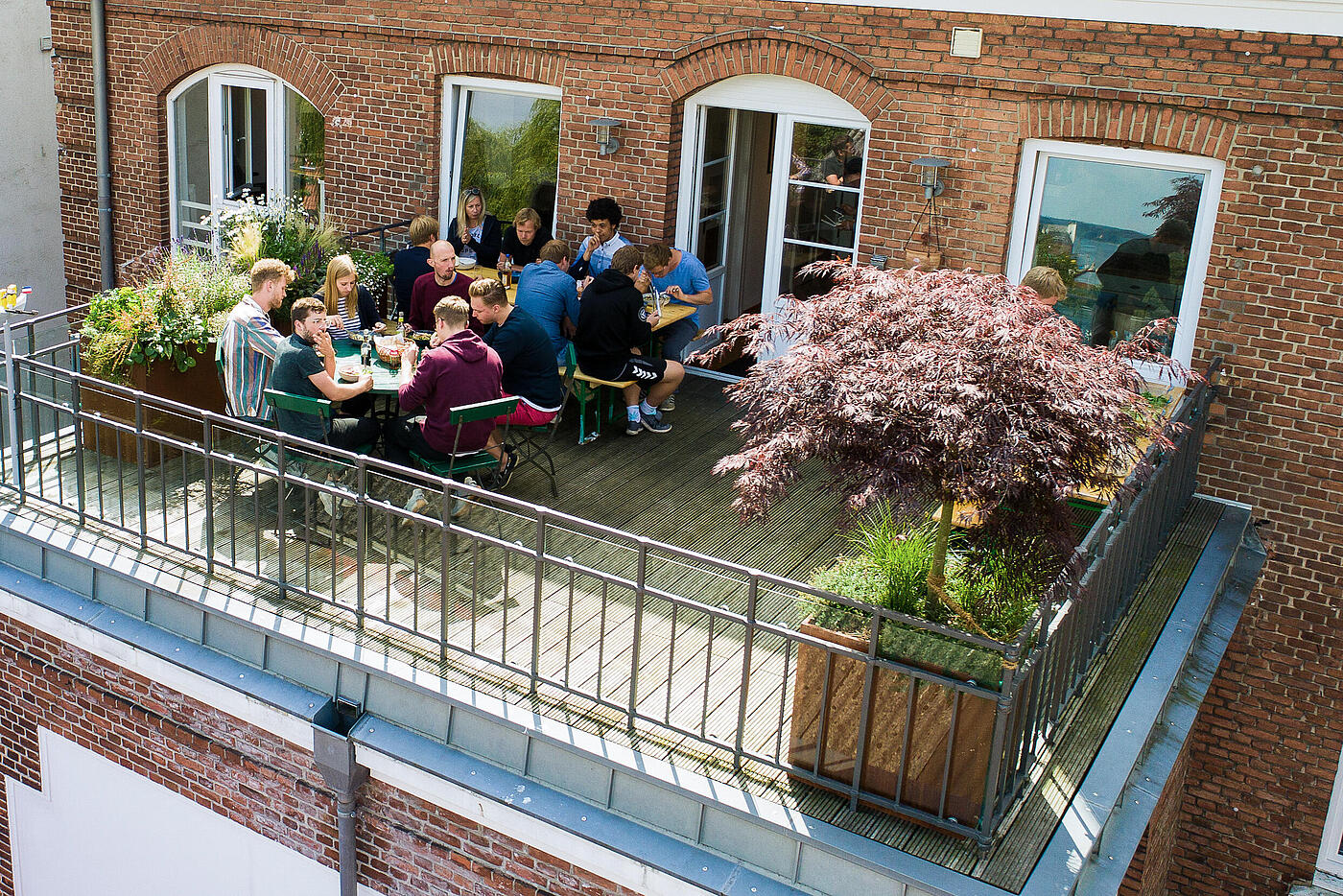 Mehrere Mitarbeiter von visuellverstehen essen zusammen auf dem Balkon.