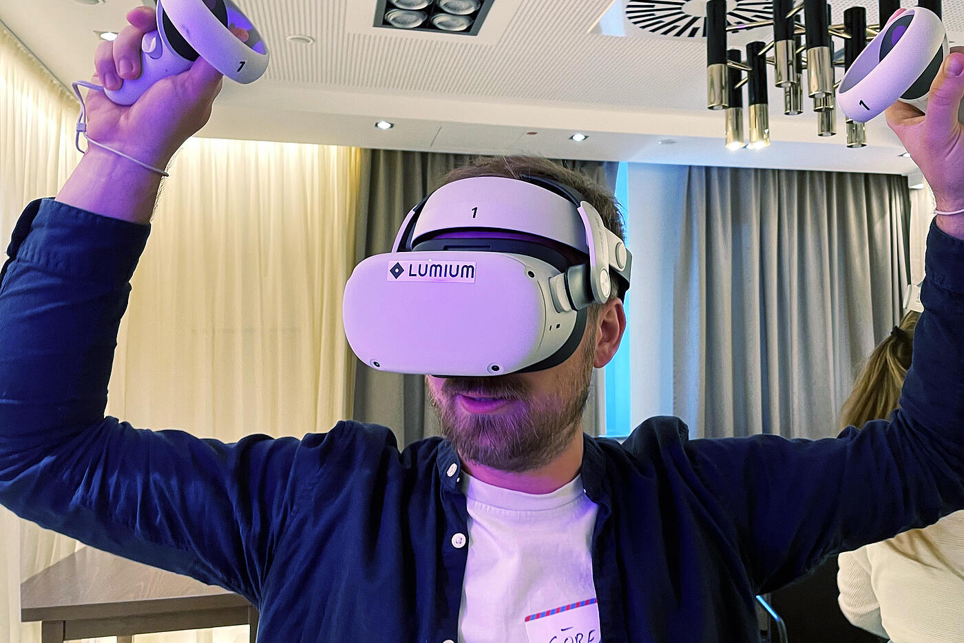 Einer der Geschäftsführer von visuellverstehen trägt eine VR-Brille und hält zwei Controller in die Höhe.