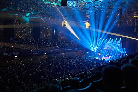 Person singt vor großem Publikum auf der Flensburg-singt-Sinatra-Veranstaltung, gehüllt in blaues Licht.