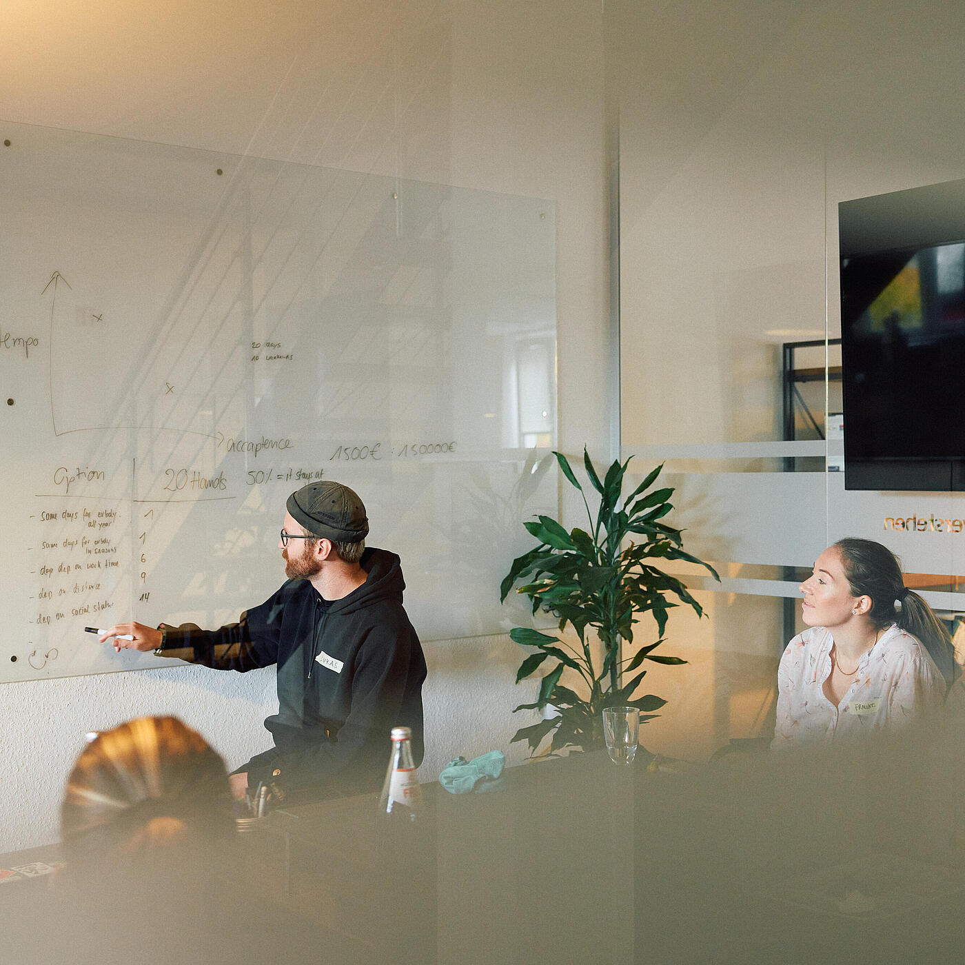 Mehrere Mitarbeitende von visuellverstehen sind in einer Besprechung. Ein Mitarbeiter visualisiert etwas an einem Whiteboard.