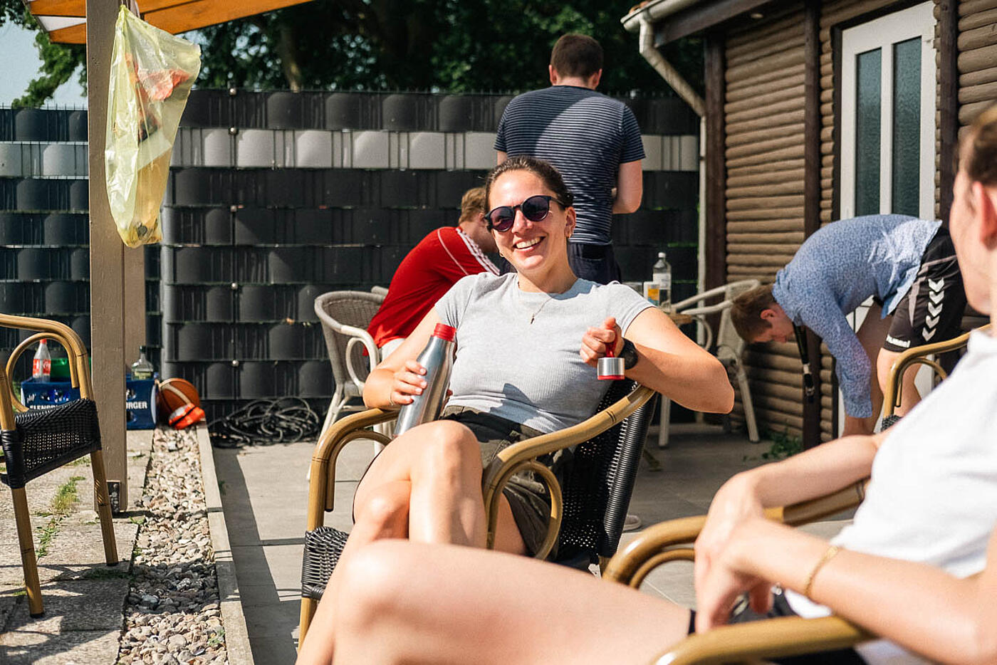 Mitarbeitende von visuellverstehen beim Sommerfest 2022 sitzen in gemütlicher Runde im Freien in der Sonne.
