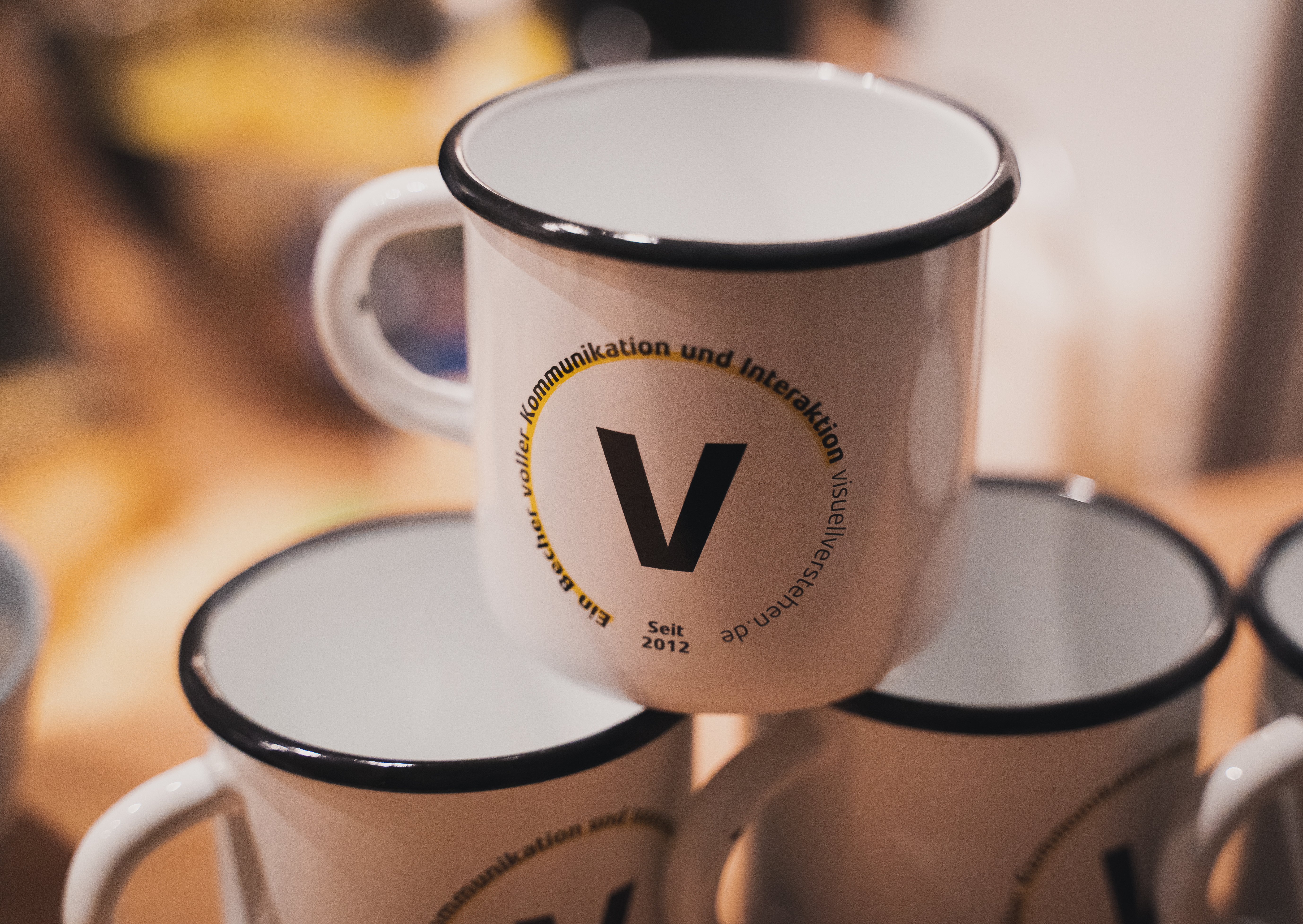 Kaffeebecher mit dem visuellverstehen-Logo zur Pyramide aufgetürmt.