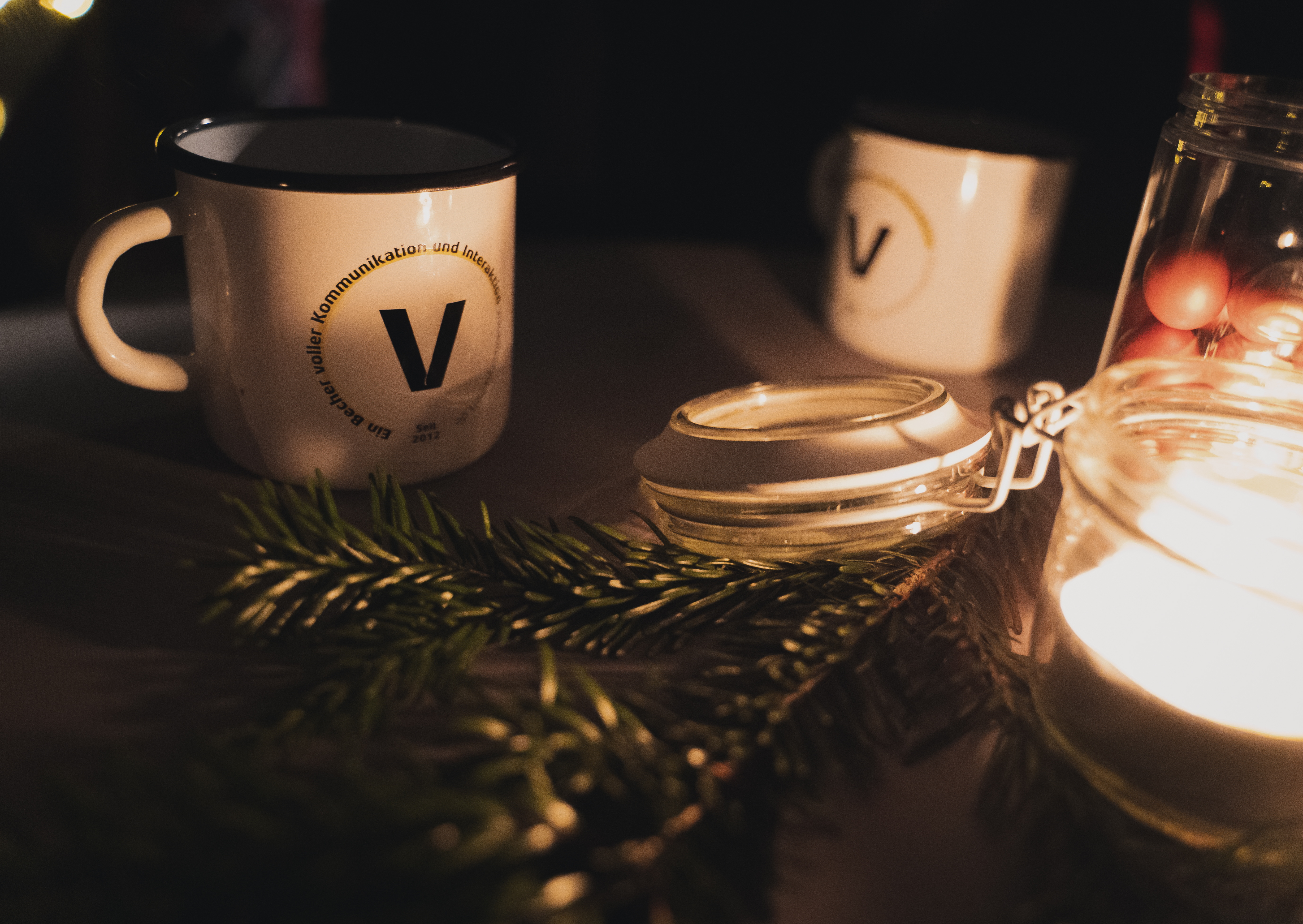 Kaffeebecher mit dem visuellverstehen-Logo inmitten von weihnachtlicher Deko.