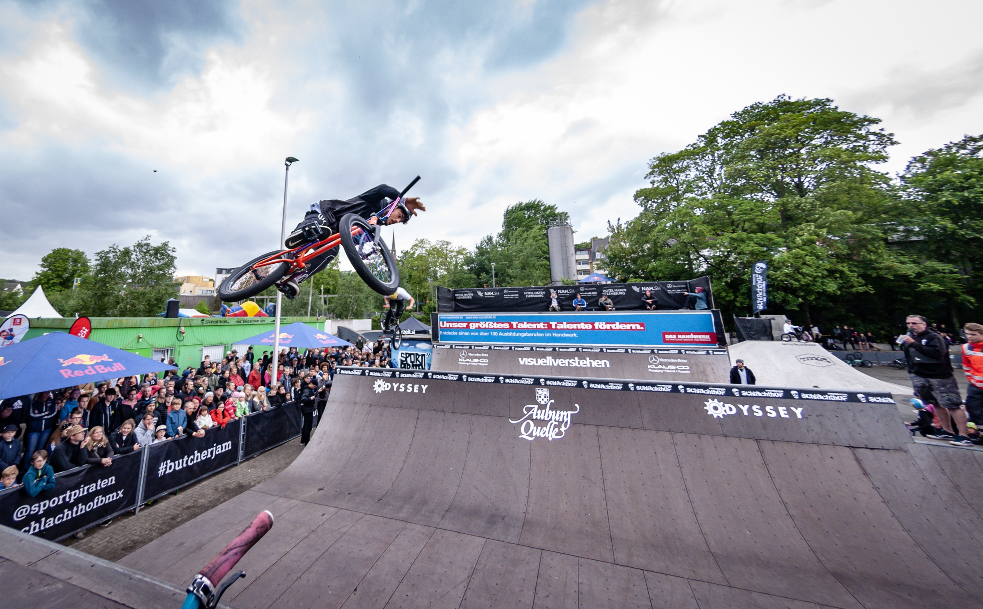 Ein BMX-Fahrer dreht sich am oberen Rand einer Halfpipe in der Luft.